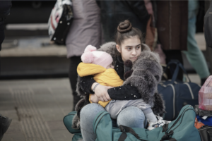A young woman sits holding her young daughter surrounding my luggage