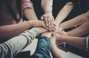 Close up of multiple hands put together in solidarity in the middle of a circle