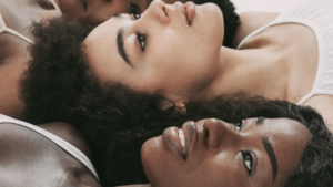 Three women lying with their heads together gazing upwards