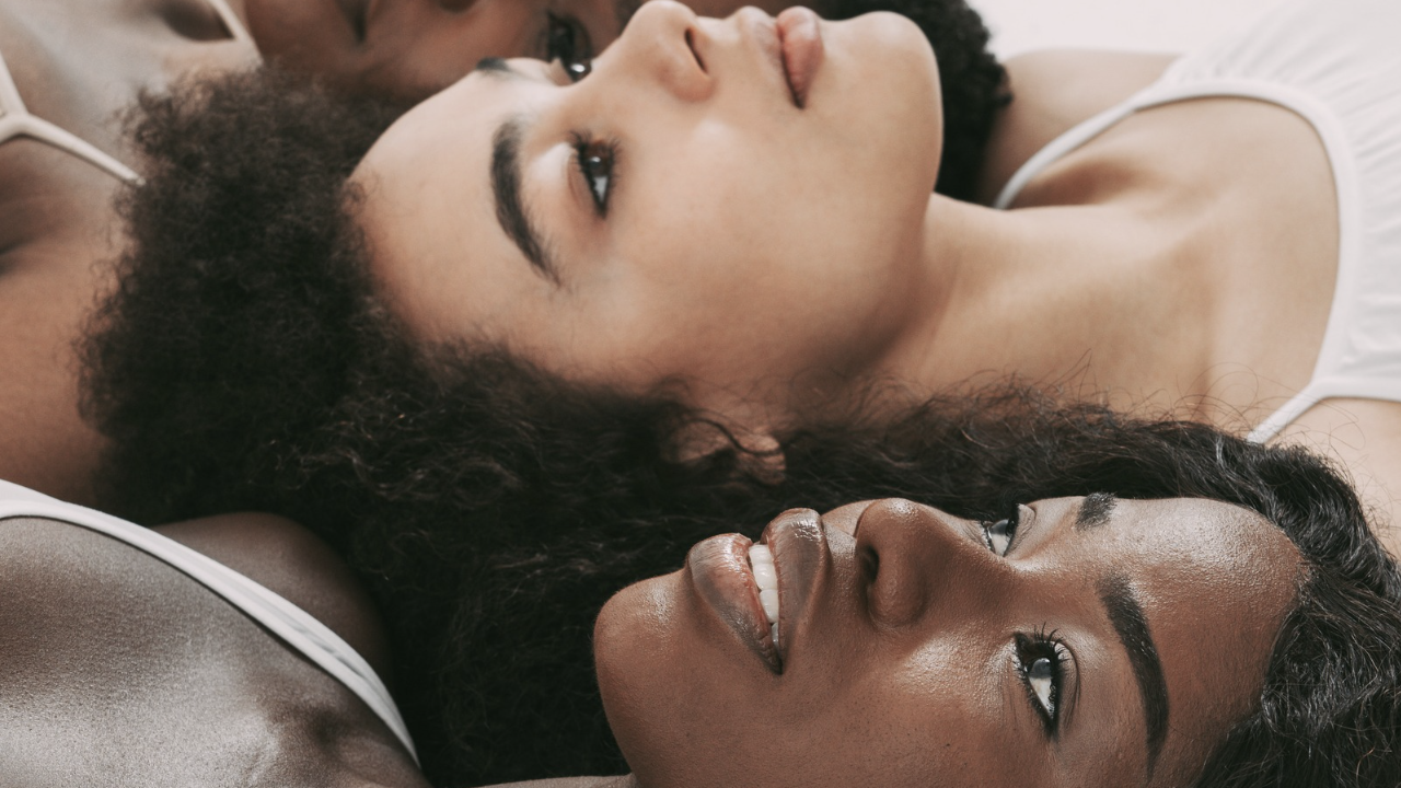 Three women lying with their heads together gazing upwards